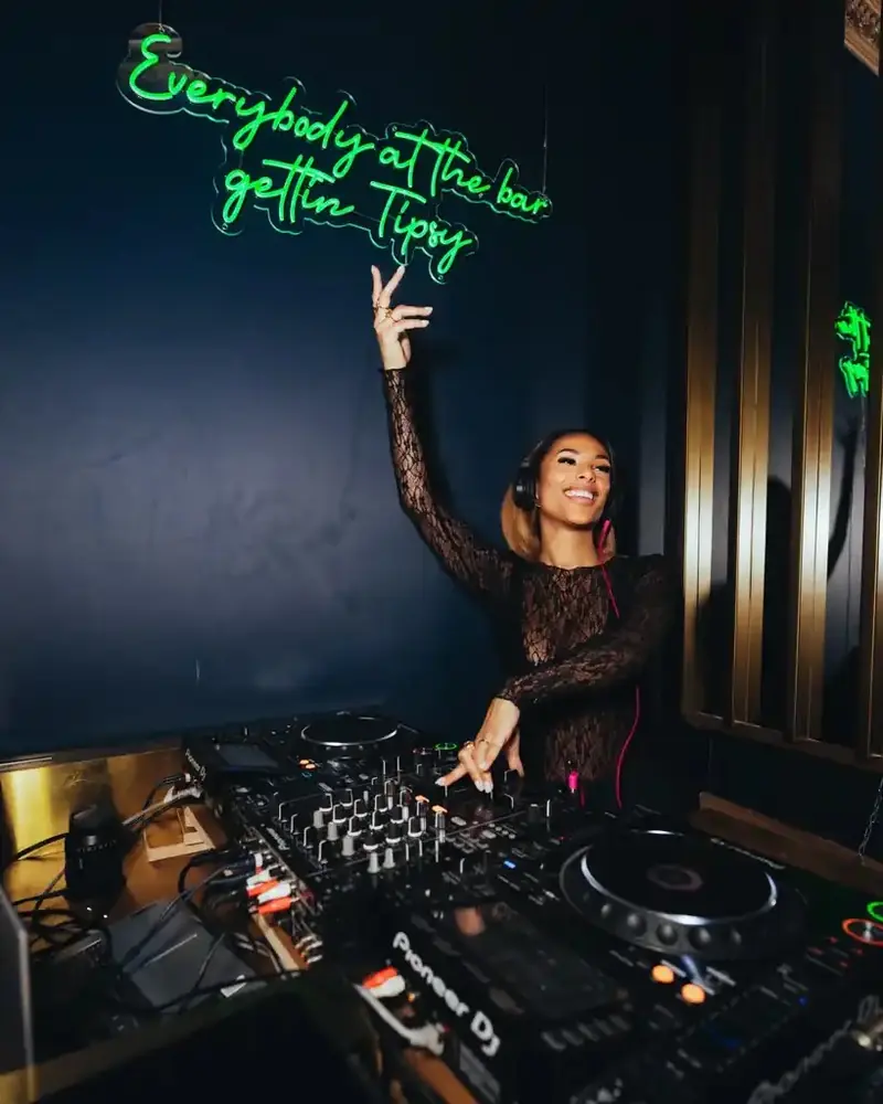 Resident DJ AMIYA under the Tipsy Thursday neon