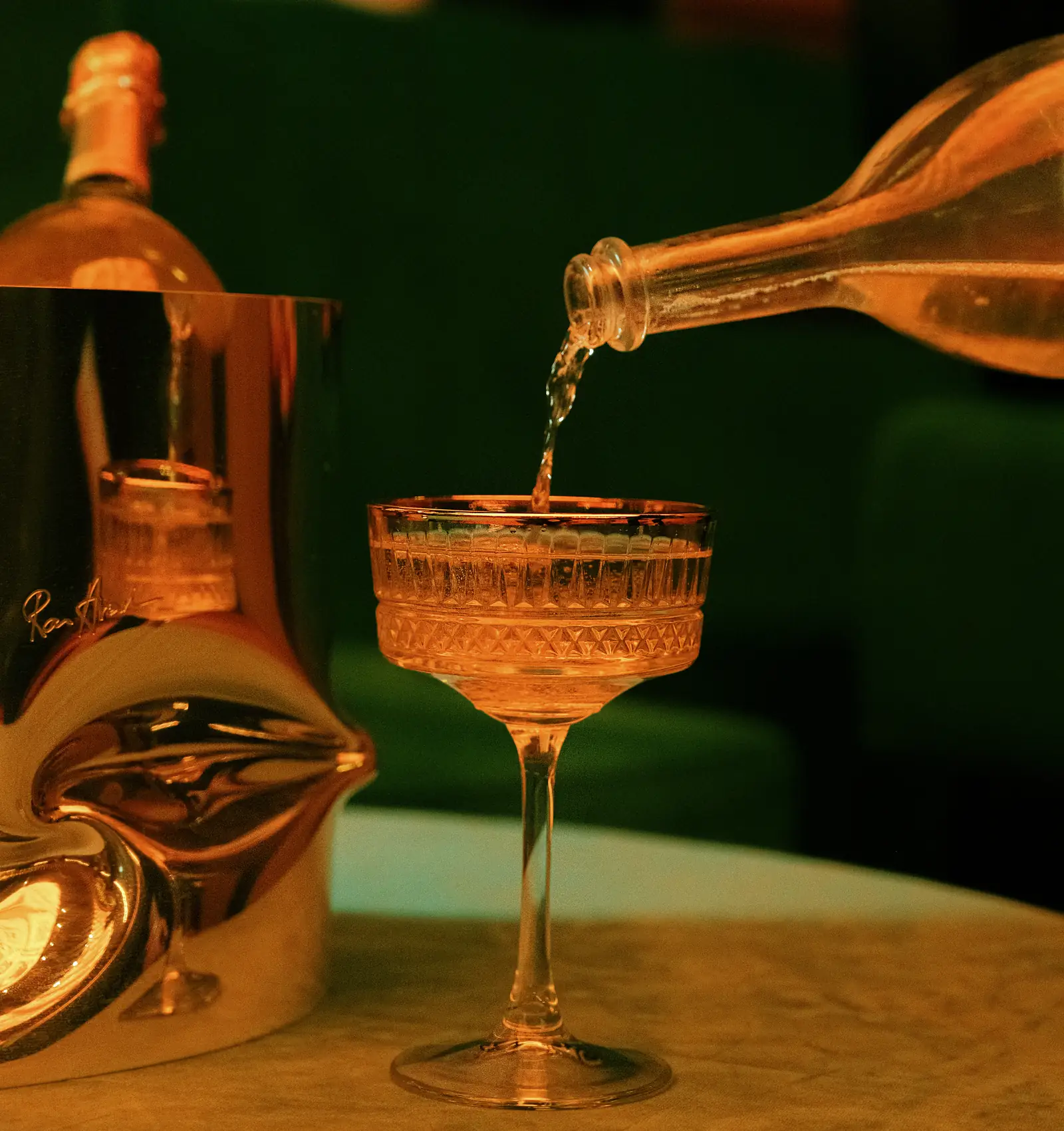 Champagne poured into a coupe next to a silver ice bucket at Mayfair